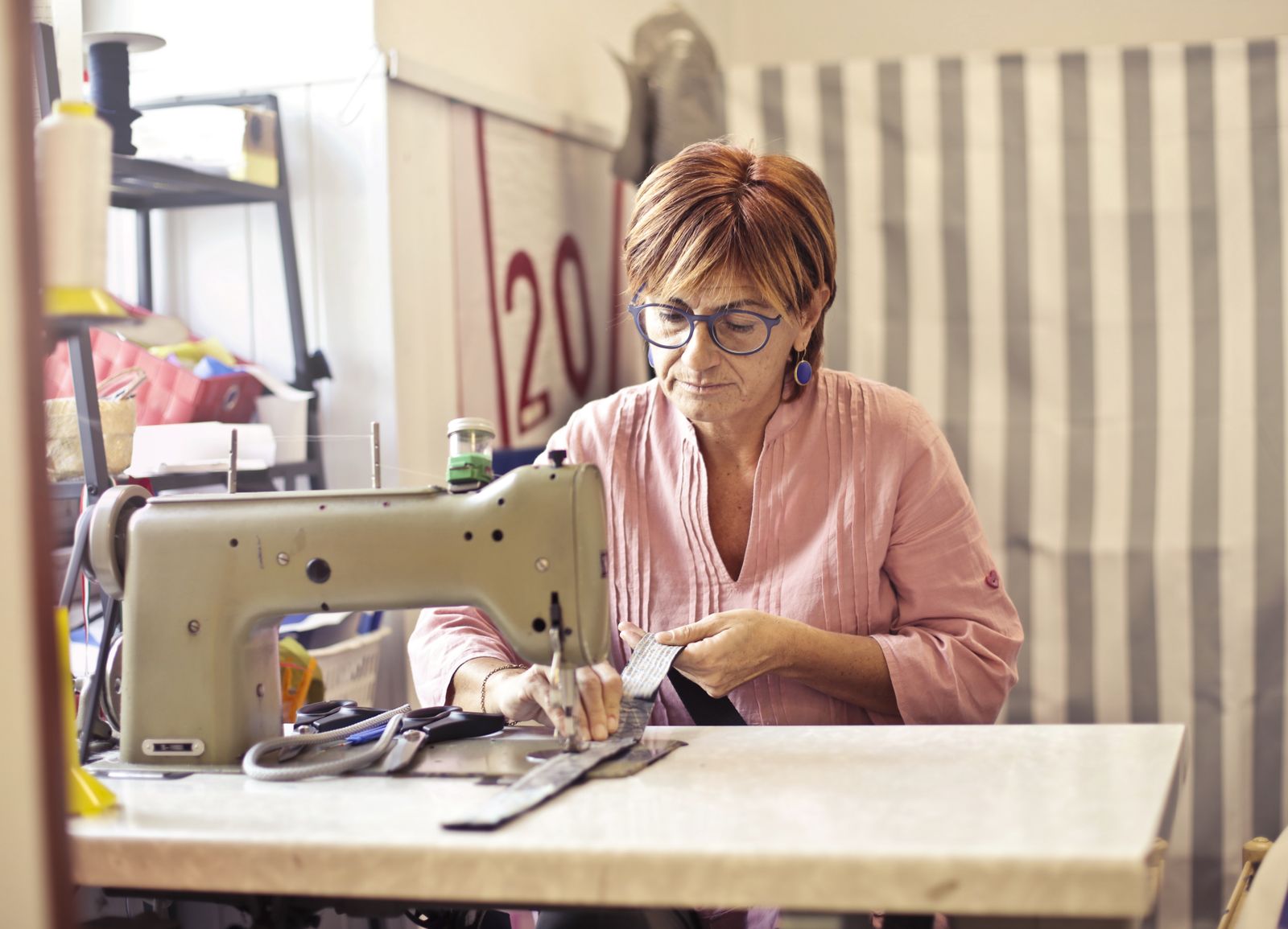 Fotografía de referencia: una costurera confecciona una prenda con una máquina de coser en un taller